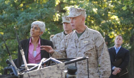 a group of people standing in front of a military vehicle at the pentagon.