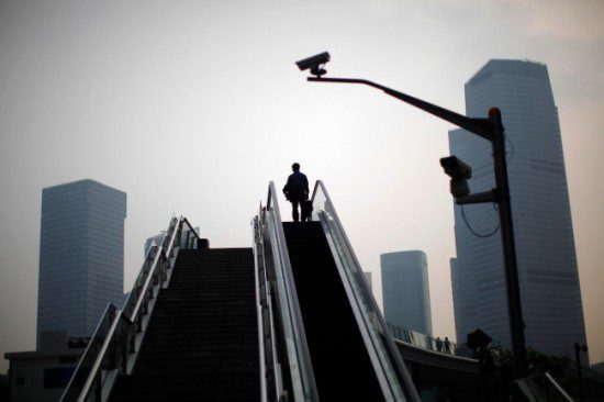 a man is walking down an escalator in hong kong, surrounded by citizens.